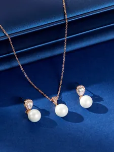Detailopname van elegante parelsieradenset met roze goudkleurige ketting en oorbellen