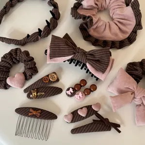 Elegant pink and brown striped hair accessories set with bows and hearts, flat lay detail.
