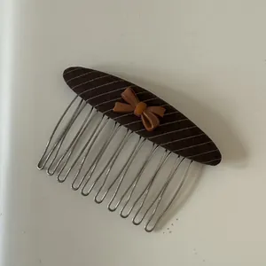 Detailed macro view of a brown striped hair comb decorated with a small elegant bow.