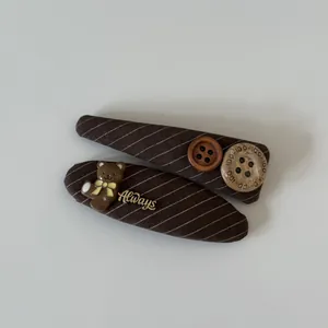 Close-up detail of brown striped fabric hair clips with a cute bear and buttons