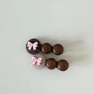 Detailed view of two cute hair clips with pink bows and brown glossy beads