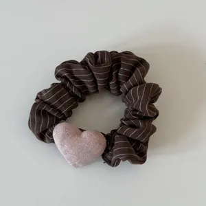 High-quality detailed view of a dark brown pinstriped scrunchie with a pink heart