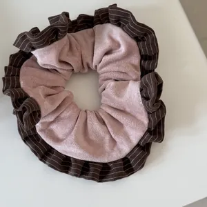 Close-up of pink scrunchie with brown striped ruffled edges