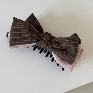 Detailed view of pink and brown striped bow hair claw clip with velvet texture