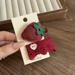 Nahaufnahme süßer roter Haarklammern mit Erdbeer-Stickerei und Spitzenherzknopf