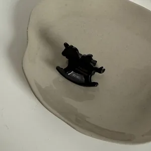 Détail d'une pince à cheveux vintage en acétate en forme de cheval noir sur un plat.