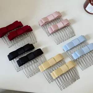 Top view of five pairs of satin bow hair combs in red, pink, black, blue, and yellow
