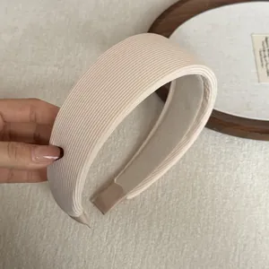 Detail view of a wide cream padded sponge headband with elegant ribbed fabric texture.