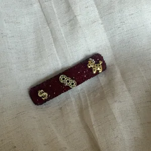 Detail van de rode sprankelende haarspeld met gouden dollar- en poedelbedeltjes.