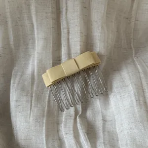 Close-up detail of a soft yellow satin bow hair comb on a textured linen background