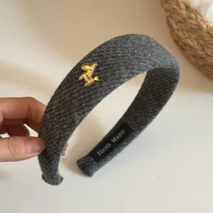 Close-up of gray knitted headband with golden horse charm and hand made label