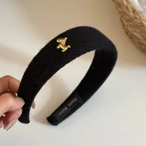 Close-up of a premium black ribbed knitted headband featuring a gold pony charm
