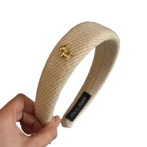 Minimalist beige twill wide headband featuring a stylish gold horse charm detail