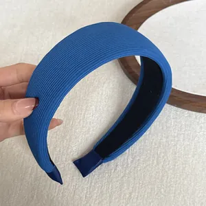 Detailed macro view of a blue ribbed wide sponge headband held by hand on white