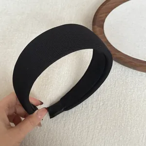 Close-up detail of a minimalist black ribbed wide sponge headband showing soft fabric texture