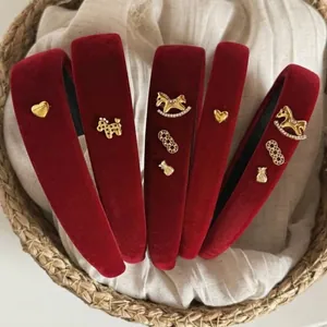 Détail de serre-têtes en velours rouge avec breloques dorées dans un panier.