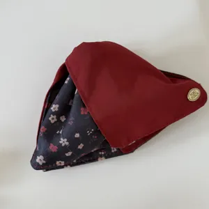 Detail view of retro floral and burgundy fabric hair accessory with metal logo badge.