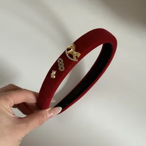Détail d'un serre-tête vintage en velours rouge avec breloques dorées et design rembourré