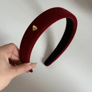 Vue détaillée d'un serre-tête en velours rouge rétro avec un petit cœur doré.