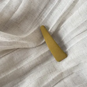 Vue détaillée d'une pince à cheveux BB jaune moutarde en tissu sur fond de lin.