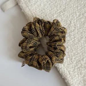 Close-up of yellow checkered fabric scrunchie with high-quality texture details.