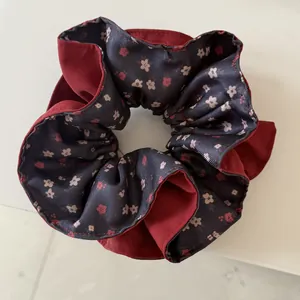 Close-up of a floral retro scrunchie with elegant burgundy and dark blossom patterns