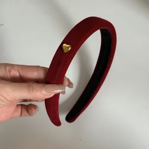 Vue détaillée d'un serre-tête en velours rouge avec un ornement en métal cœur doré