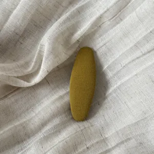 Vue détaillée d'une pince à cheveux BB jaune gingembre recouverte de tissu sur lin