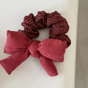 Detailed macro view of a wine red striped fabric scrunchie with a large suede bow knot