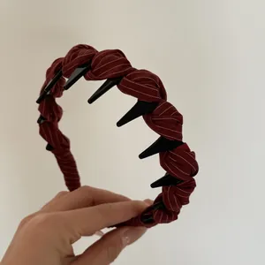 Close-up detail of burgundy striped fabric headband featuring black shark teeth grips