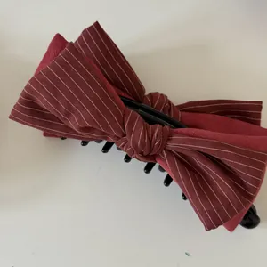 Close-up of burgundy striped and solid fabric bow on a large black hair claw clip.