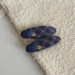 Detailed macro view of purple plaid fabric hair clips featuring denim heart and gold accents