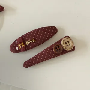 Detailed shot of burgundy striped fabric BB hair clips with cute bear and button charms