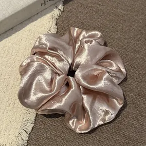Detailopname van champagne satijnen haarelastiekje met elegante strass steentjes