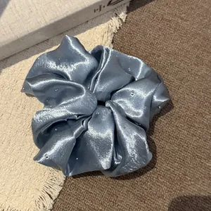 Gedetailleerd overzicht van een lichtblauwe satijnen scrunchie met delicate strasaccenten
