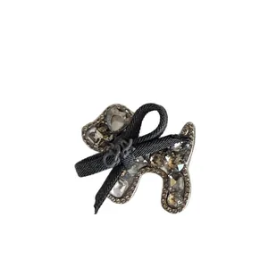 Barrette élégante en forme de chien teddy avec strass gris et nœud noir pour femme.