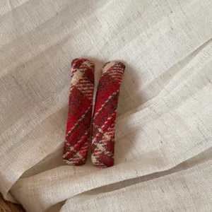 Detailopname van twee vintage rode geruite BB-haarspeldjes op linnen achtergrond