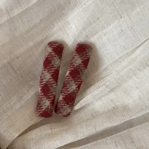 Detailopname van een paar rood geruite stoffen haarspeldjes op een getextureerde basis.