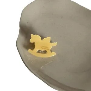 Petite pince à cheveux en acétate de cellulose forme cheval à bascule vintage sur plateau