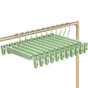 Set of 10 light green non-slip pant hangers with adjustable clips for closet storage