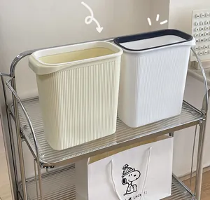 Dos cubos de basura minimalistas de plástico crema y blanco con ranuras en un estante