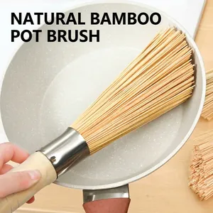 Natural bamboo kitchen cleaning brush being used to scrub a non-stick frying pan