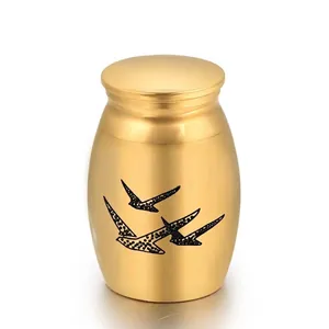Detailed close-up view of a small gold memorial cremation urn with engraved black birds