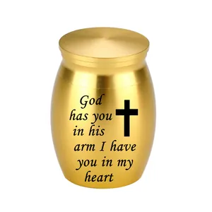 Detail view of golden memorial urn with cross and God has you in his arm inscription