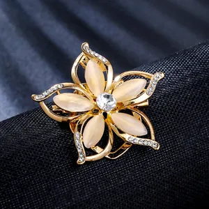 Macro view of a luxury golden flower brooch featuring cat-eye stones and rhinestones