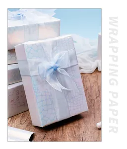 Gedetailleerd overzicht van iriserend blauw cadeaupapier met krokodillenprint op dozen