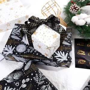 Papier cadeau de Noël haut de gamme avec étoiles dorées et motifs de feuillage noir élégant.