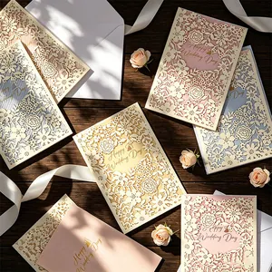 Detail view of French laser-cut wedding invitations in pastel colors with envelopes.