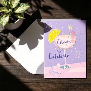 Tarjeta de felicitación de cóctel violeta con sobre en una mesa de madera al sol