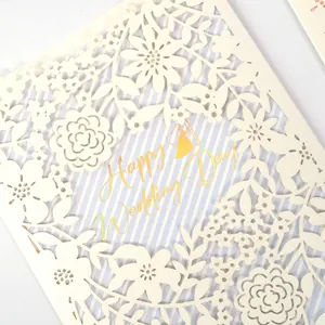 Detail view of elegant cream laser-cut floral wedding invitation card with gold text